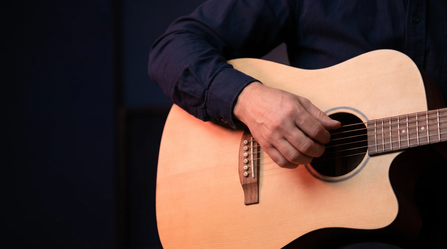 Close-up of an adult hand playing the strings of an acoustic guitar.