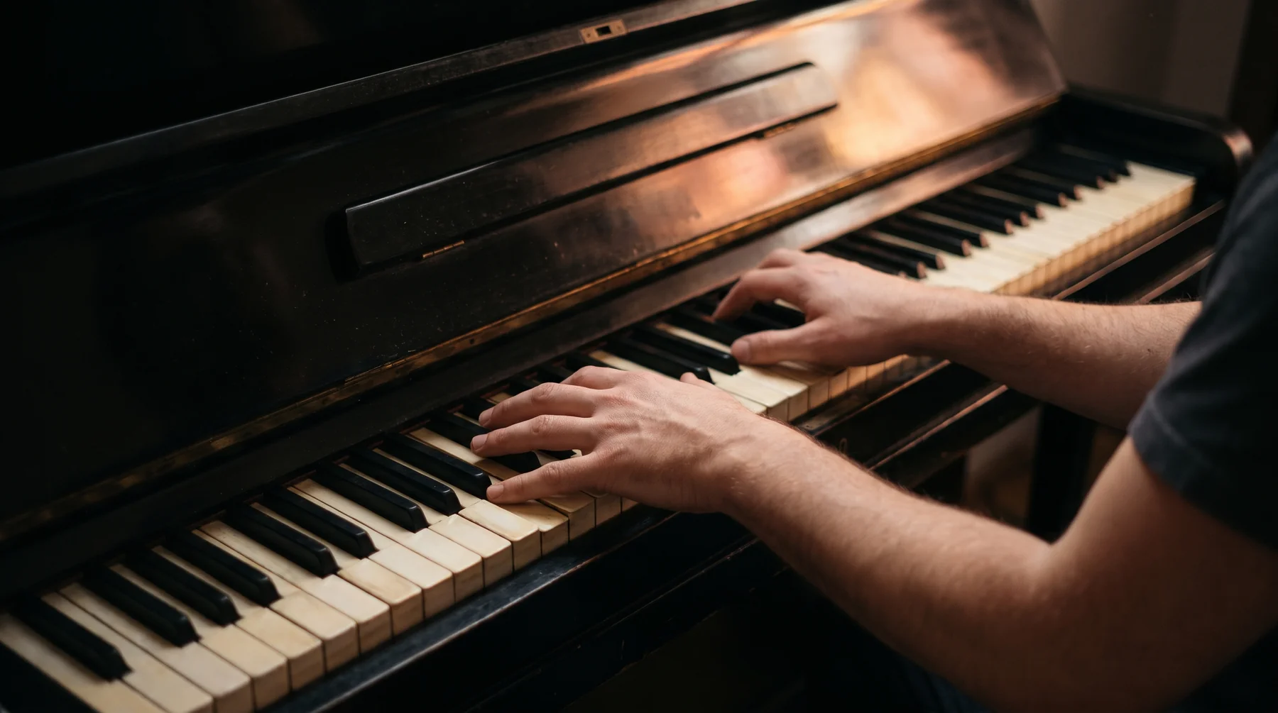 An adult practising on an upright piano keyboard.
